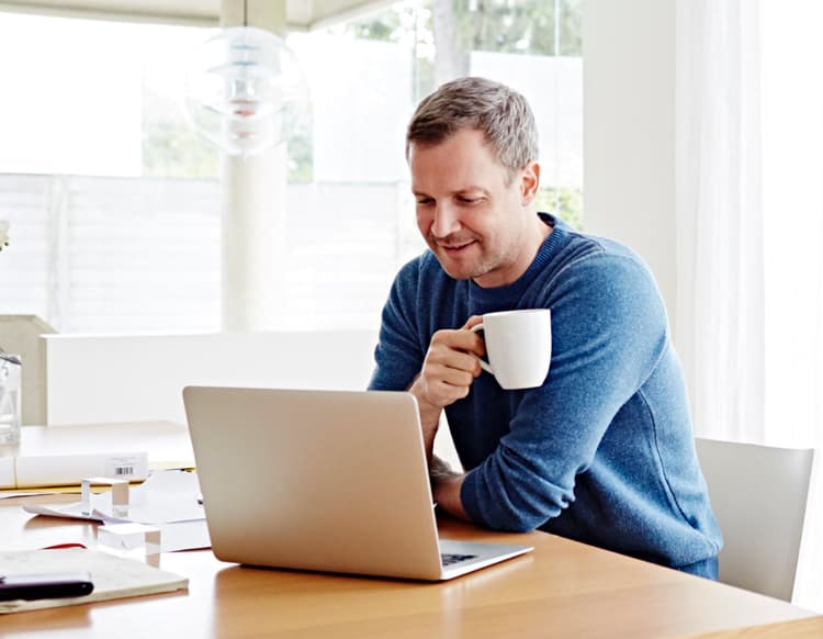Man looking at a computer while drinking his coffee.