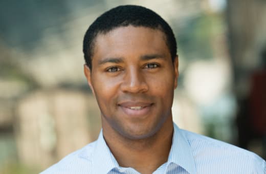 A man in his 20s smiling while standing outdoors.